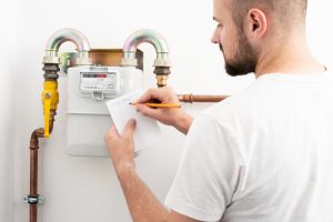 man installing a gas meter and writing down a reading